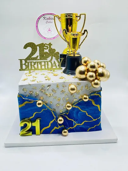 Blue and white marble cake with gold veining and trophy toppers